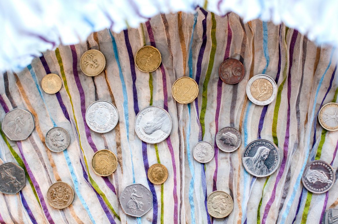 Currency risk management: A number of coins in different currencies scattered on a table