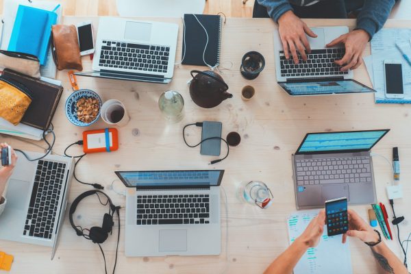 Innovative Finance ISAs (IFISAs): Shared office desk, cluttered with several laptops, smartphones, coffee cups and headphones