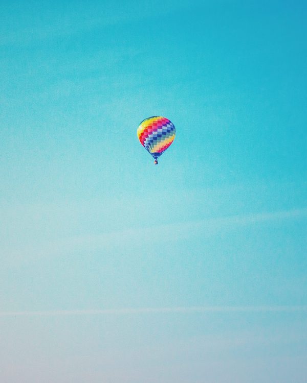 Examples of crowdfunding: Multi-coloured hot air balloon sailing along against a clear blue sky