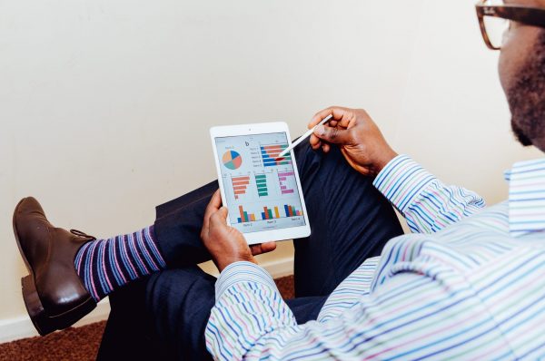 HNWI vs Sophisticated Investor: Man sitting in chair, looking as this tablet