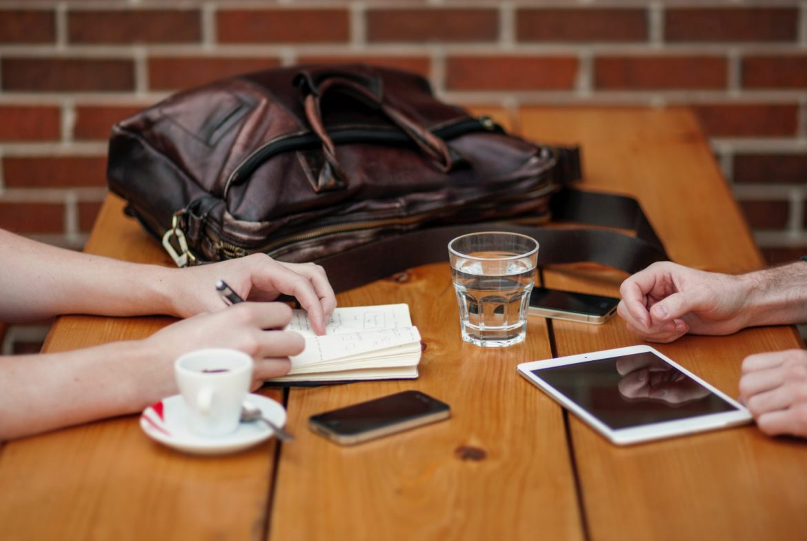 Investing in rare earth metals: two people sitting at a table with phones and laptops on display