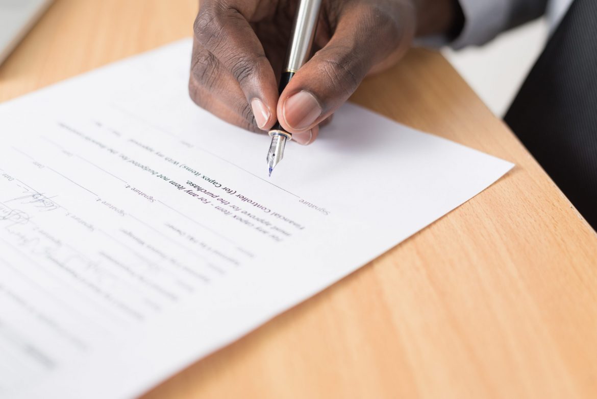 Compensation order: Man sitting at a desk about to sign an official document
