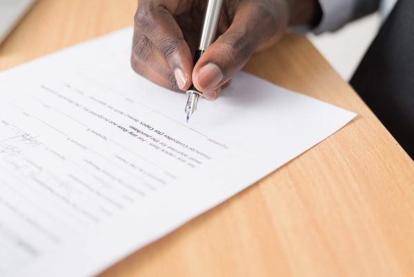 Compensation order: Man sitting at a desk about to sign an official document