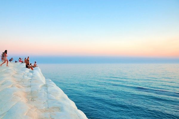 Peer-to-peer lending: Group of people sitting on a limestone cliff looking out to sea