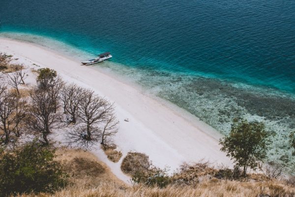 Property fraud: Cliff top view of a deserted white sand beach with clear blue water