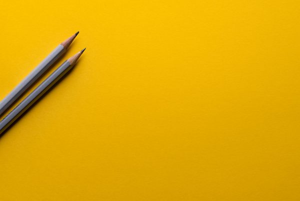 Investing in cryptocurrencies: How to invest in cryptocurrency: Two grey pencils set against a mustard yellow background
