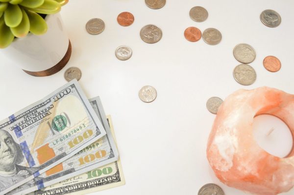 Investment Apps: A selection of coins, notes and a small plant seedling on a table