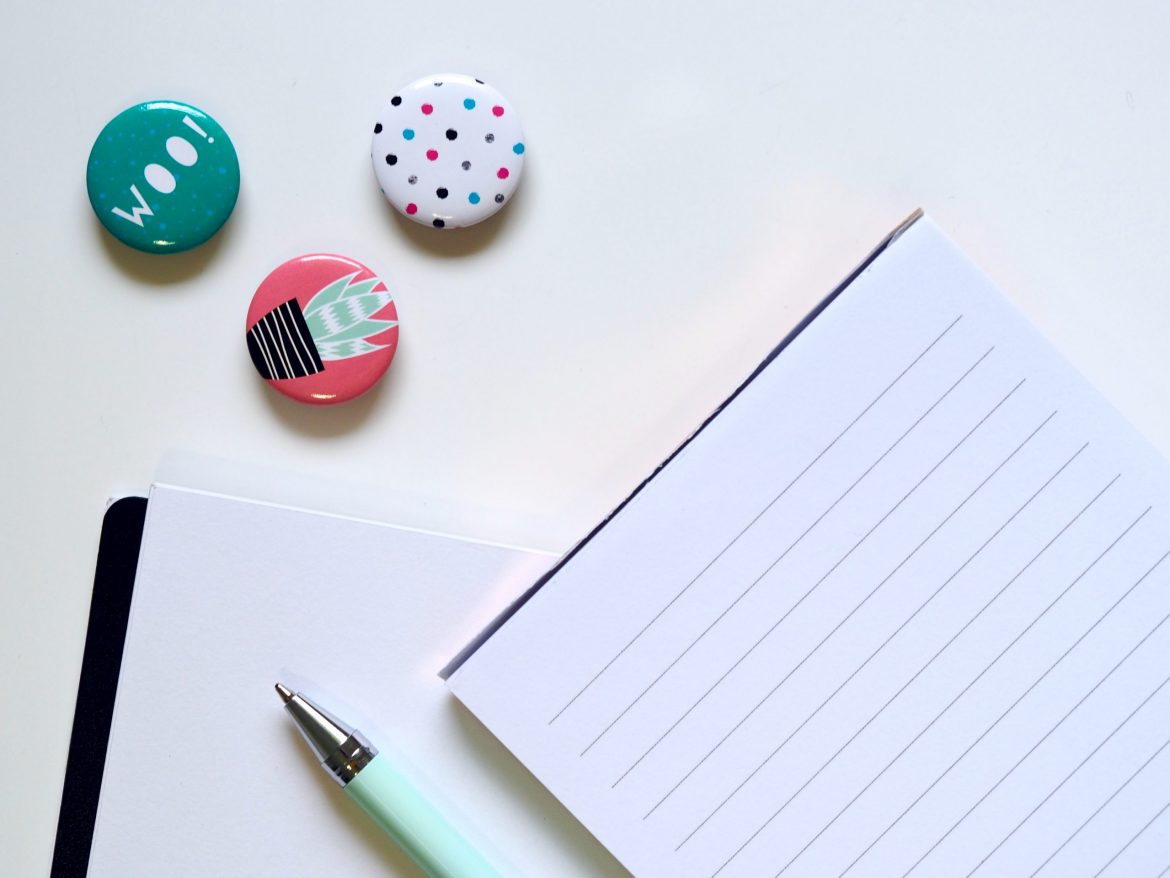 types of bonds: series of items on a white desk including button badges, note pad and pen