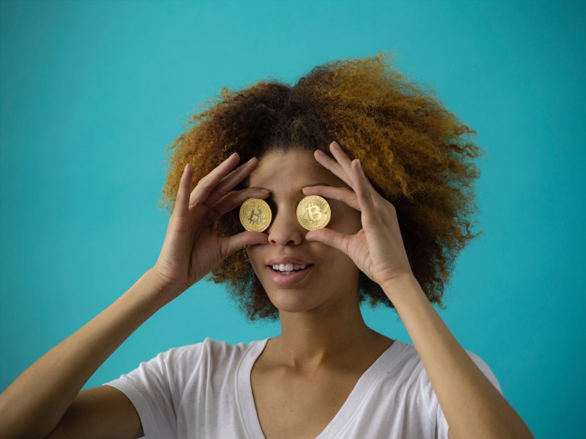 Examples of cryptocurrency: Gil holding two bitcoin coins to her eyes like binoculars