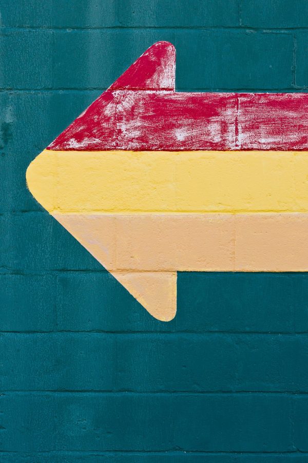 Stocks and share capital: Multi-coloured arrow painted on to a blue wall